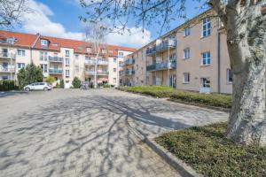a tree casts a shadow on a brick road in front of buildings at Larooms Merseburg - Apartment NP62 - ServiceApartment für Geschäftsreisende in Merseburg