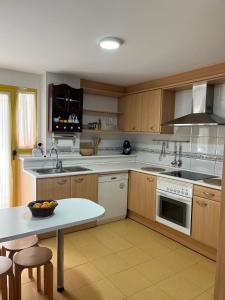 a kitchen with wooden cabinets and a table and a sink at Ático duplex Lagos del Castillo in Denia