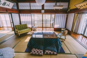 a room with a table and a couch and windows at 山形イチマルニマル in Miyajuku