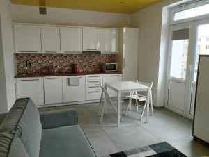 a kitchen with white cabinets and a table with chairs at Studio Świętojańska in Gdynia