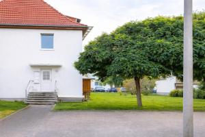 a white house with a tree in the yard at Larooms Merseburg - Apartment LP01 - 2 Zimmer, 2 Einzelbetten, 1 Doppelbett, große Couch, Küche, Balkon, Waschmaschine in Merseburg
