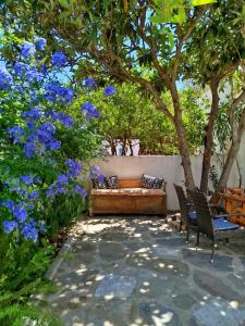a garden with two chairs and a couch under a tree at Almond trees house in Órmos Aiyialís