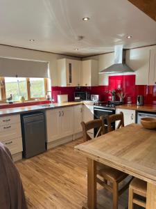 a large kitchen with a wooden table and a wooden floor at Tigh a Chabar in Lochaline +16 photos