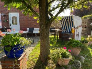 a garden with a tree and a table and chairs at Zum Fahrensmann in Norddorf