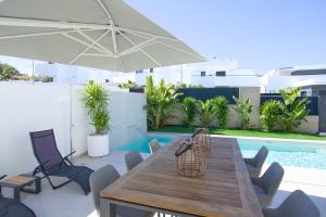 a patio with a wooden table and chairs and an umbrella at L'au D'evi in Rojales