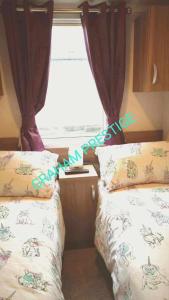 a bedroom with two beds and a window at Grahams Prestige Craig Tara in Minishant