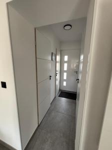an empty hallway with white walls and a door at L Orée des Thermes in Saint-Amand-les-Eaux
