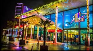 a building with palm trees in front of it at night at L Orée des Thermes in Saint-Amand-les-Eaux