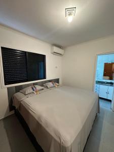 a bedroom with a large white bed with a window at Cobertura Premium com Piscina Exclusiva in Guarujá +47 photos