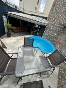 a patio with a table and chairs and a swimming pool at Cobertura Premium com Piscina Exclusiva in Guarujá
