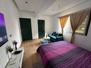 a bedroom with a large bed and a blue couch at CNS Guest House in Grand-Bassam