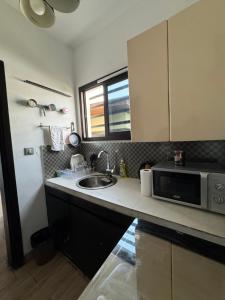 a kitchen with a sink and a microwave at CNS Guest House in Grand-Bassam