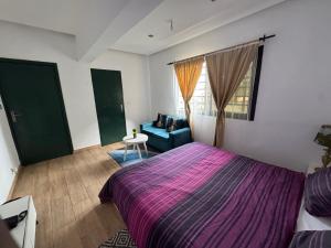 a bedroom with a purple bed and a blue couch at CNS Guest House in Grand-Bassam