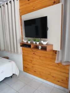 a flat screen tv on a wooden wall in a bedroom at Casa Nas Montanhas Capixabas in Domingos Martins