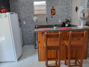 a kitchen with a refrigerator and a counter with two chairs at Casa Nas Montanhas Capixabas in Domingos Martins