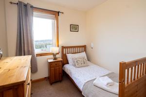 a bedroom with a bed and a desk and a window at Owlswood Lodge in Orkney