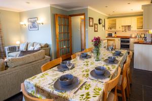 a dining room with a table with chairs and a kitchen at Owlswood Lodge in Orkney