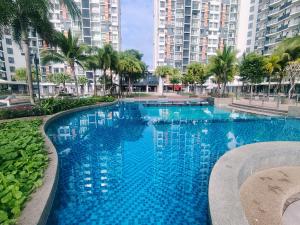 a large blue swimming pool with palm trees and buildings at Timurbay Seafront By Moonlight in Kuantan