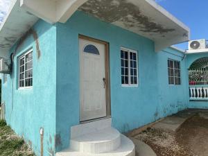 a blue house with a white door at Reggae Moon Guesthouse in Falmouth