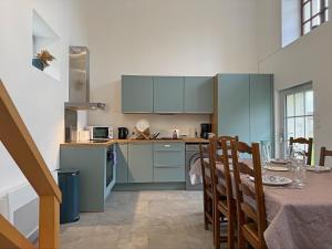 a kitchen with blue cabinets and a table with a dining room at Le Domaine de l'Ormurion in Sourdun