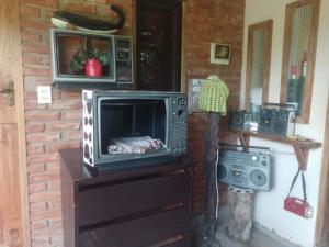 a television on a dresser with a microwave on top of it at Cabaña Renacer in Samaipata