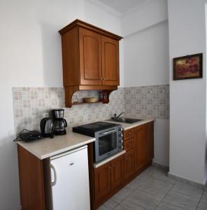 una piccola cucina con mobili in legno e un forno a microonde di SeasoundStudios ad Agios Stefanos