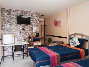 a bedroom with two beds and a tv on a brick wall at สมหวัง โฮมสเตย์ in Ban Khuan Suan