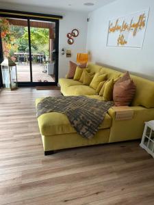 a living room with a yellow couch and wooden floors at Chiswick Garden Studio with Outdoor Pool and Boutique Finish in London