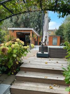 a wooden walkway with an umbrella in a garden at Chiswick Garden Studio with Outdoor Pool and Boutique Finish in London