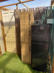 a garage with a black refrigerator and a door at Karoo Stone camper in Ladismith