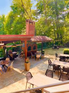 a patio with tables and chairs and a brick fireplace at Hotel Restaurant Vodenitsata in Berkovitsa
