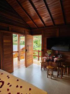 a dining room with a table and a television at Chales Vista da Mata 01 in Santa Teresa