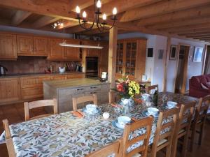 a dining room with a table and chairs and a kitchen at Chalet Le Murier in Leysin