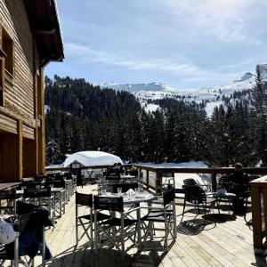a patio with tables and chairs on a deck at Hôtel LAPIAZ & Spa - FLAINE in Flaine