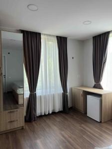 a bedroom with a window with curtains and a mirror at Nebi Winery in Chʼardakhi