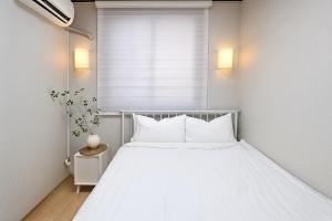 a white bed in a room with a window at Sai-gil stay in Busan