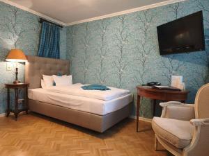 a bedroom with a bed and a tv and a chair at Hotel Goldener Anker in Bayreuth