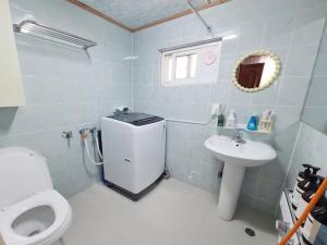 a white bathroom with a toilet and a sink at Sai-gil stay in Busan
