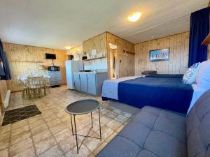 a bedroom with a bed and a couch and a kitchen at Chalets Camping Bernatchez in Mont-saint-pierre