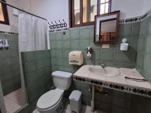 a bathroom with a toilet and a sink and a mirror at Hotel Marielos Tamarindo in Tamarindo