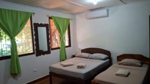 two beds in a room with green curtains at Hotel Marielos Tamarindo in Tamarindo +165 photos