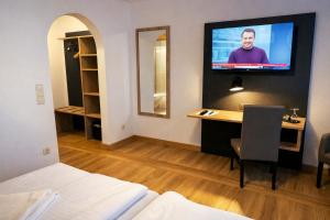 ein Hotelzimmer mit einem Bett und einem Fernseher an der Wand in der Unterkunft A8 Hotel im Darchinger Hof Bed & Breakfast - Zwischen Holzkirchen und Weyarn - Zwischen München Salzburg und Innsbruck - Kurz vor dem Irschenberg in Weyarn