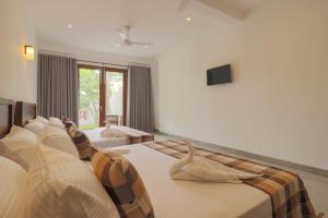 a bedroom with two beds and a tv on the wall at Haru Ahangama in Ahangama