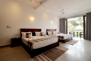 a bedroom with two beds and a large window at Haru Ahangama in Ahangama