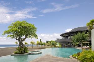 a swimming pool in front of a building next to the beach at Quenzo Beach Resort in Padangbai