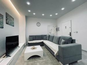 a living room with a blue couch and a tv at Paco Apartment Center Shkoder in Shkodër