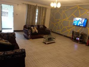 a living room with a couch and a tv at Kruse Compound in Lake View Estate