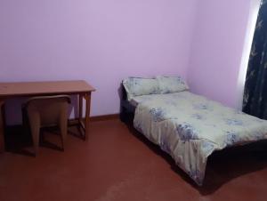 a small bedroom with a bed and a table at Kruse Compound in Lake View Estate