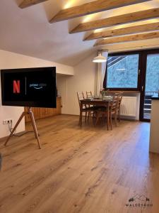 a living room with a television and a table with chairs at Waldesruh in Grünenbach