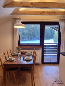 a dining room with a wooden table and a large window at Waldesruh in Grünenbach